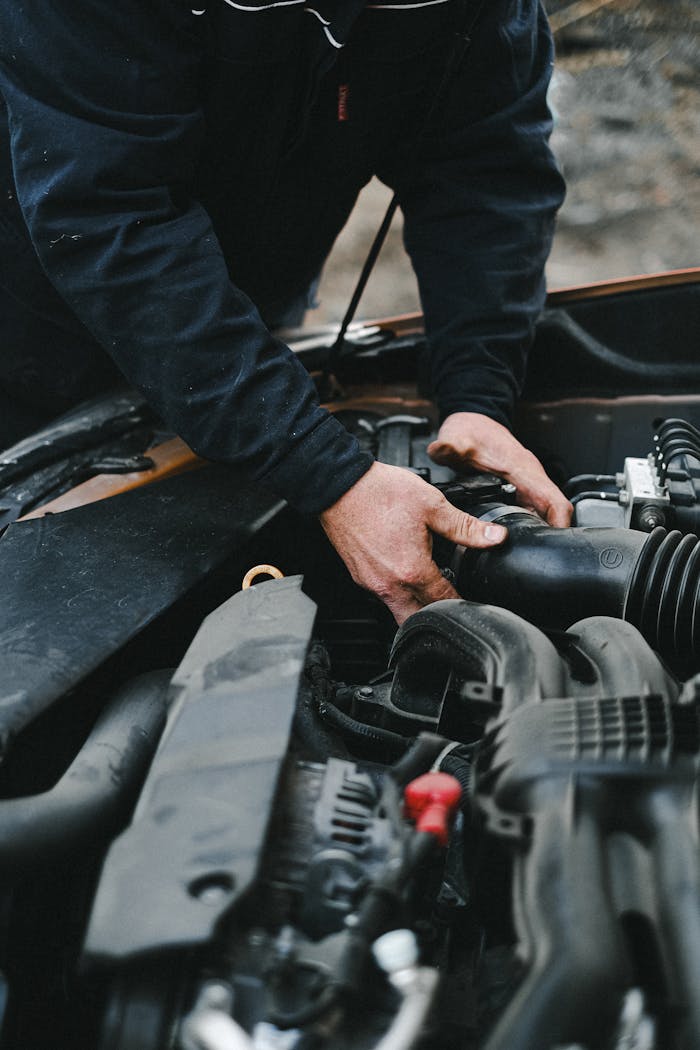 Services Close-up of a mechanic's hands working on a car engine inside a workshop.